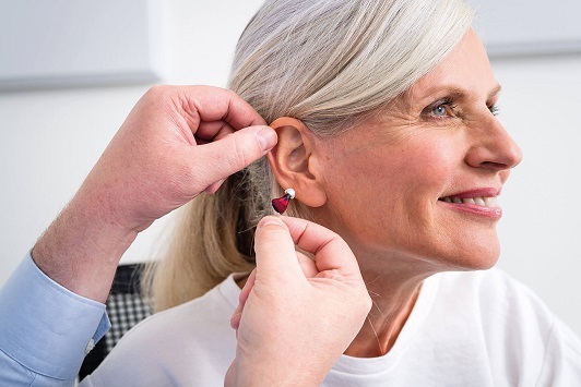 Ältere Frau erhält ein modernes Hörgerät zur Verbesserung ihres Hörvermögens angepasst.